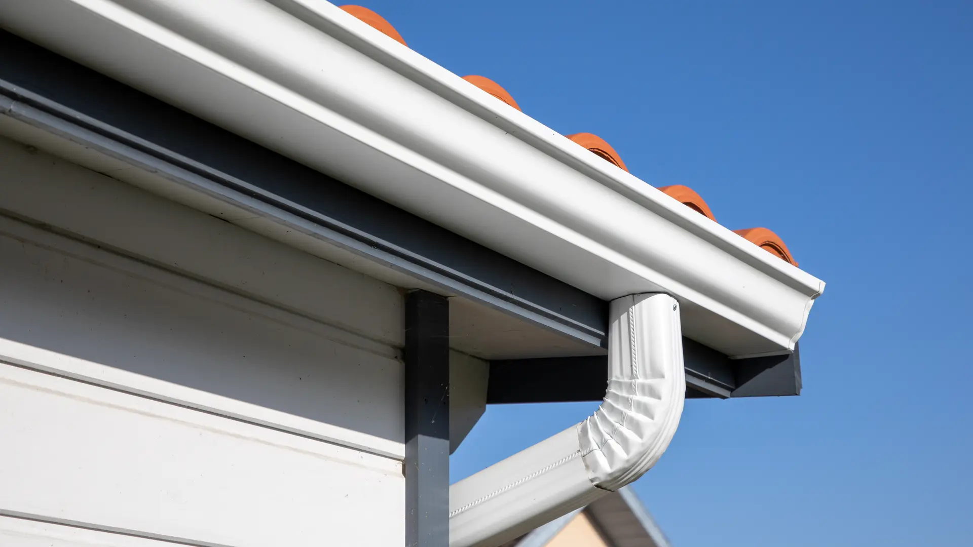 White uPVC gutter and downpipe on a house eaves