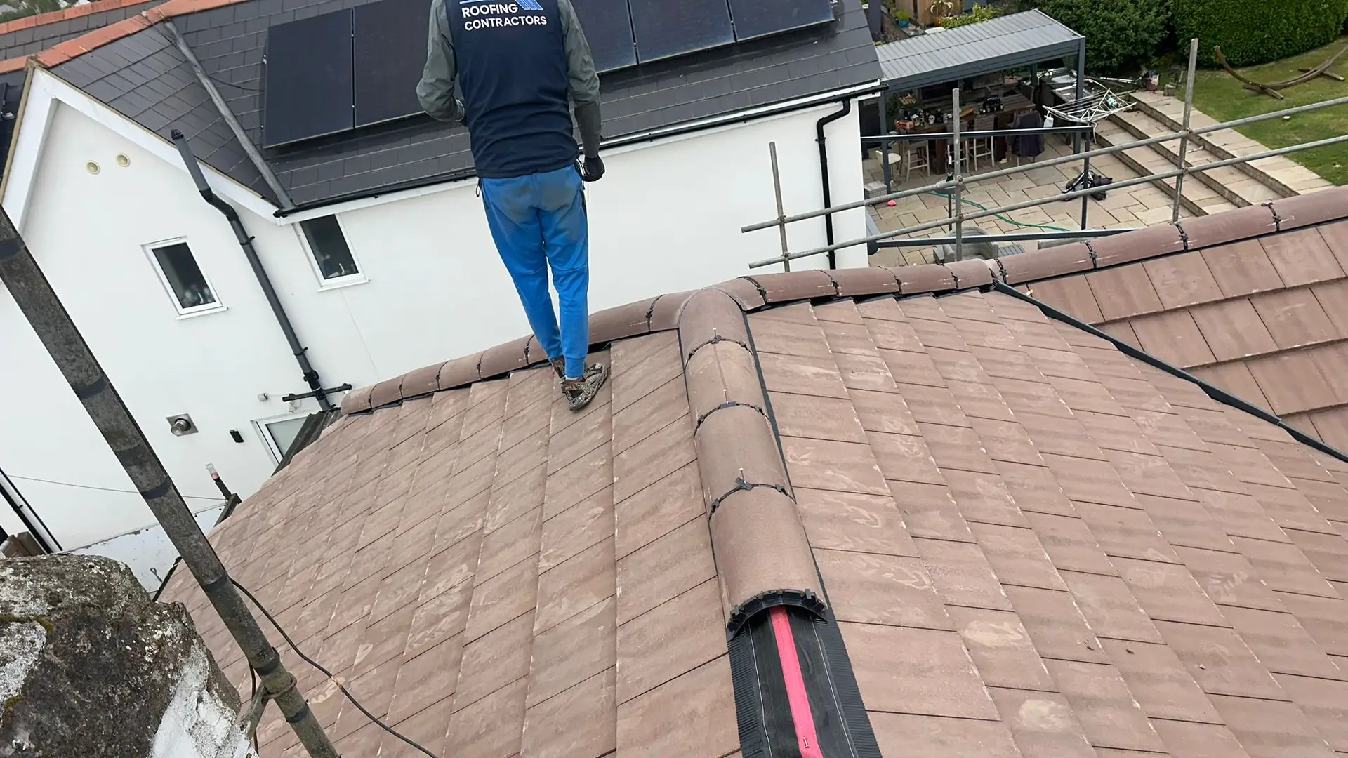 Roofer walking the ridge of a new plain tiled roof